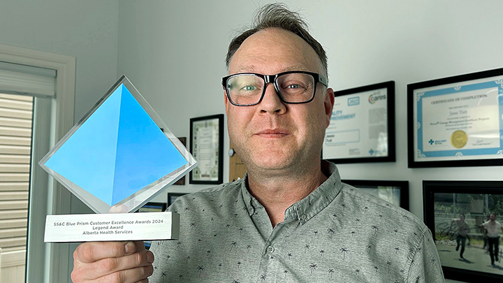 Jesse Tutt, program director of Intelligent Automation with Alberta Health Services’ IT team, proudly shows off the latest hardware AHS has added to the awards case after the organization received a Legend Award at the SS&C Blue Prism Customer Excellence Awards in May.