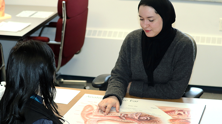 Maysem Elfurjani counsels her patient using a large illustration of the ear to build a better understanding of their condition.